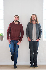 Image showing Portrait of twin brothers standing by a wall together in studio. Young twins, siblings and family of young men side by side. Relationship with brother, brotherhood and two guys who look identical