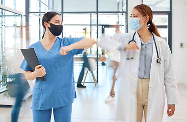 Image showing Covid healthcare doctor and nurse greeting with elbow in hospital clinic. Medical women or people with face mask and social distancing in corona virus pandemic for trust, motivation and innovation