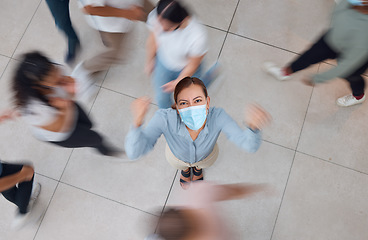 Image showing Angry business woman with a mask for covid and people walking around her. Young girl wearing face mask in a crowd, frustrated and shaking her fist. Aerial view of upset female in mall or office