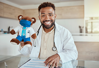 Image showing Child doctor, pediatrician and healthcare work holding a teddy bear toy and looking happy and friendly while sitting in his office in a hospital. Health, care and smile of male medical physician