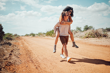 Image showing Couple, love and travel with a man and woman walking on a sand road in the dessert or nature together. Summer, romance and dating with a happy, young male giving a piggyback to a female in the wild