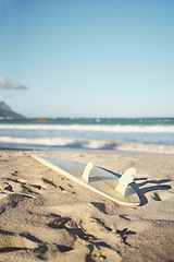 Image showing Beach, surfboard and sand in nature, summer aesthetic of Los angeles at sunset. Sport, freedom and adventure with waves in ocean to enjoy water sports, fun and stress relief in a tropical paradise