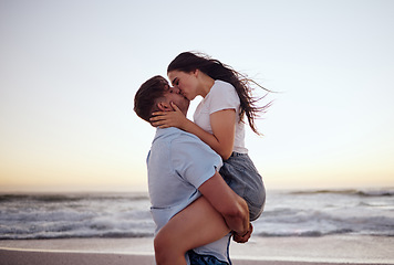 Image showing Love, couple and kiss on beach at sunset for romantic and passionate embrace on summer evening date. Dating USA woman and man enjoy dusk sky together at Los Angeles ocean with physical affection.