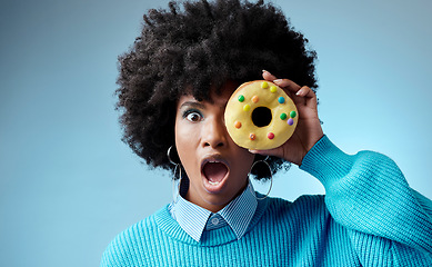 Image showing Wow, surprise and donut on eye of black woman feeling shocked with sugar, dessert or sweets against a blue background studio. Candy, food and cake with girl and omg emotion for deal, sale or alert