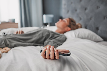 Image showing Phone, bed and woman sleeping in a bedroom, exhausted and suffering with mental health problem. Tired, lazy and procrastination by depressed lady ignoring alarm, experience fatigue from insomnia