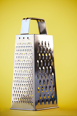 Image showing Metal or steel cheese grater for grocery cooking, food preparation and culinary help or support. Silver, metallic or home kitchenware appliance with cut pattern shredder isolated on yellow background