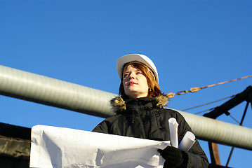 Image showing Young architect looking at blueprint in front of construction si