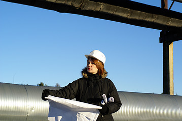 Image showing Young architect looking at blueprint in front of construction si