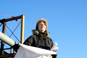 Image showing Young architect looking at blueprint in front of construction si