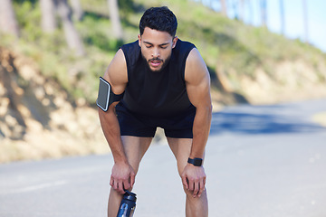 Image showing Road, runner and tired man on a break after running exercise, cardio training and workout outdoors in nature. Sports, fitness and out of breath athlete with fatigue resting and holding a water bottle