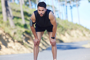 Image showing Fitness, exercise and tired with a sports man taking a break from his workout, training or running on a road in nature. Health, wellness and breathing with a young male athlete resting during his run