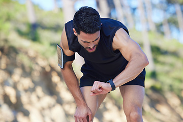 Image showing Exercise, watch and time with a sports man tracking his fitness on a sport app while running outdoor in nature. Training, workout and health with a male athlete timing his run, speed or distance