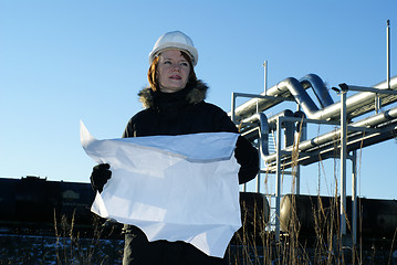 Image showing Young architect looking at blueprint in front of construction si