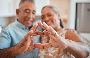 Image showing Hands, heart and love with a senior couple in their retirement home together for health, wellness and romance. Fingers, sign and affection with a mature man and woman pensioner bonding in their house