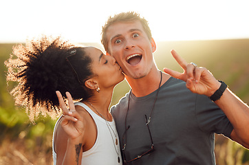 Image showing Funny, kiss and couple bonding during vacation on a farm with peace sign. Happy interracial husband and wife standing close together on vineyard in summer. Young husband and wife feeling in love