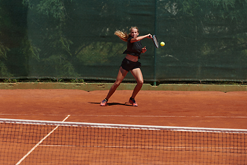 Image showing A young girl showing professional tennis skills in a competitive match on a sunny day, surrounded by the modern aesthetics of a tennis court.