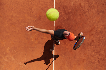 Image showing Top view of a professional tennis player serves the tennis ball on the court with precision and power