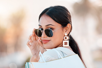 Image showing Woman, fashion and shopping happy with sunglasses on face in city after sale, discount and bag from shop. Girl, beauty and portrait with style, confidence and smile in time at mall, store or boutique