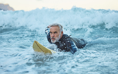 Image showing Beach, surfer and old man on surfboard swimming in nature enjoying dangerous water sports and retirement. Training, fitness and senior athlete surfing on the sea waves with freedom in Los Angeles