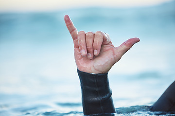 Image showing Shaka, surf and man in ocean with hand sign outdoor in nature while on vacation in Australia. Surfing culture, hang loose gesture and closeup of hands of friendly surfer in water at beach on holiday.