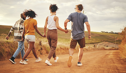 Image showing Support, holding hands and friends on a vacation in the countryside walking on a dirt road. Nature, freedom and happy group of people in the desert on a summer holiday, journey or adventure.