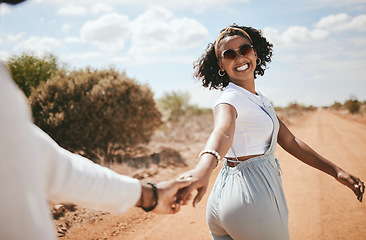 Image showing Couple, walking and nature with a black woman and man outdoor holding hands on a sand road in a dessert together. Travel, love and romance with a female and male on a date during summer vacation