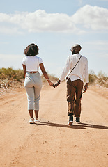 Image showing Black couple, love and holding hands back view in nature walking on vacation on desert, sand or dirt road. Romance, safari and man, woman and bonding, care or spending time together on outdoors date.