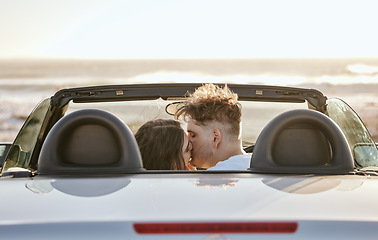 Image showing Couple, love and kiss for travel in the sunset by the beach relaxing together and embracing relationship. Man and woman kissing in loving romance for bonding, traveling and road trip in the outdoors