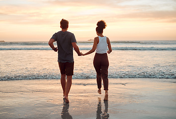 Image showing Sunset, beach and couple walking holding hands in ocean for outdoor holiday, date or summer vacation with horizon, sky mock up. Love, care and support people running, bonding by the sea for wellness