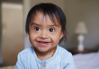 Image showing Happy, portrait smile and Down syndrome baby relaxing on a bed in happiness at home. Cheerful little child with genetic disorder or disability smiling in bedroom for cute childhood and development