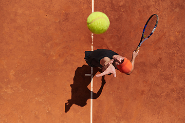 Image showing Top view of a professional tennis player serves the tennis ball on the court with precision and power