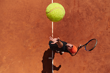 Image showing Top view of a professional tennis player serves the tennis ball on the court with precision and power