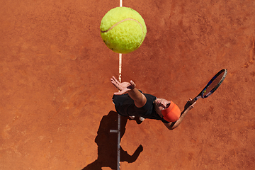 Image showing Top view of a professional tennis player serves the tennis ball on the court with precision and power