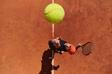 Image showing Top view of a professional tennis player serves the tennis ball on the court with precision and power