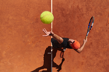 Image showing Top view of a professional tennis player serves the tennis ball on the court with precision and power