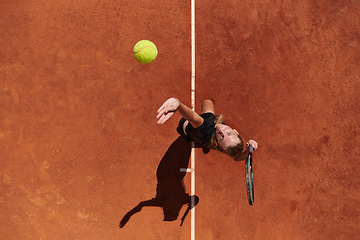 Image showing Top view of a professional female tennis player serves the tennis ball on the court with precision and power