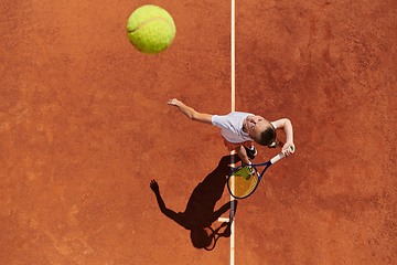 Image showing Top view of a professional female tennis player serves the tennis ball on the court with precision and power