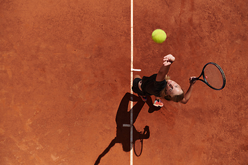 Image showing Top view of a professional female tennis player serves the tennis ball on the court with precision and power