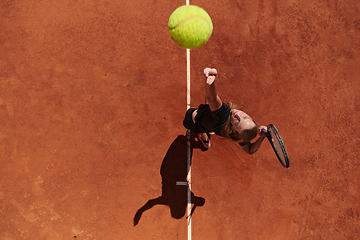 Image showing Top view of a professional female tennis player serves the tennis ball on the court with precision and power