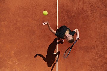 Image showing Top view of a professional female tennis player serves the tennis ball on the court with precision and power