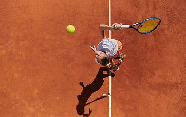 Image showing Top view of a professional female tennis player serves the tennis ball on the court with precision and power