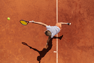 Image showing Top view of a professional female tennis player serves the tennis ball on the court with precision and power