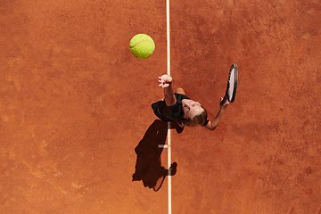 Image showing Top view of a professional female tennis player serves the tennis ball on the court with precision and power