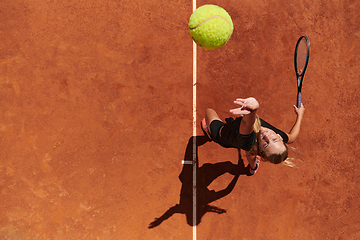 Image showing Top view of a professional female tennis player serves the tennis ball on the court with precision and power