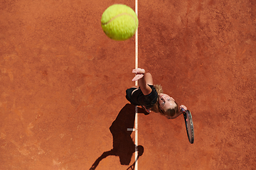 Image showing Top view of a professional female tennis player serves the tennis ball on the court with precision and power