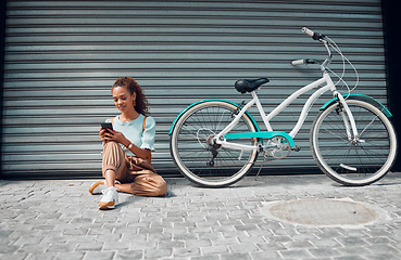 Image showing Bike, young woman and with phone in city relax, with bicycle and happy texting, social media apps and chat. Casual girl, lady and with eco friendly transportation, trendy or edgy look sit on sidewalk