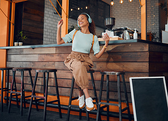 Image showing Coffee shop, headphones and woman listening to music on smartphone for customer service experience and happy with wifi in cafe. Happy gen z girl or student relax in a restaurant using phone and audio