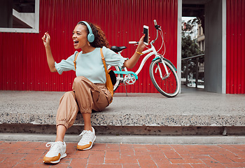 Image showing Black woman in city, listen to music on headphones and relax on street sidewalk waiting for a taxi. Girl streaming podcast, musician online and happy dance song from smartphone 5g internet connection