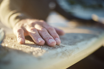 Image showing Hand, surfboard and sports with a man surfer cleaning sand from his board after surfing at the beach during summer. Sport, travel and vacation with a male outdoor in nature to surf, relax or have fun