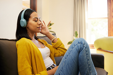 Image showing Woman, music and relax with headphones on living room sofa enjoying calm relaxation at home. Young female relaxing on a couch listening to calming audio track at the house for stress relief